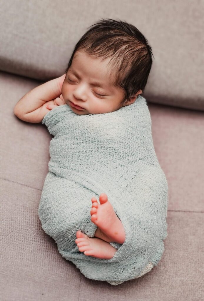 Serene newborn baby wrapped in a cozy knit blanket, peacefully sleeping indoors.
