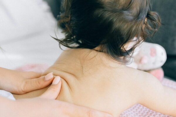 A gentle massage being given to a baby on a soft blanket, promoting relaxation.